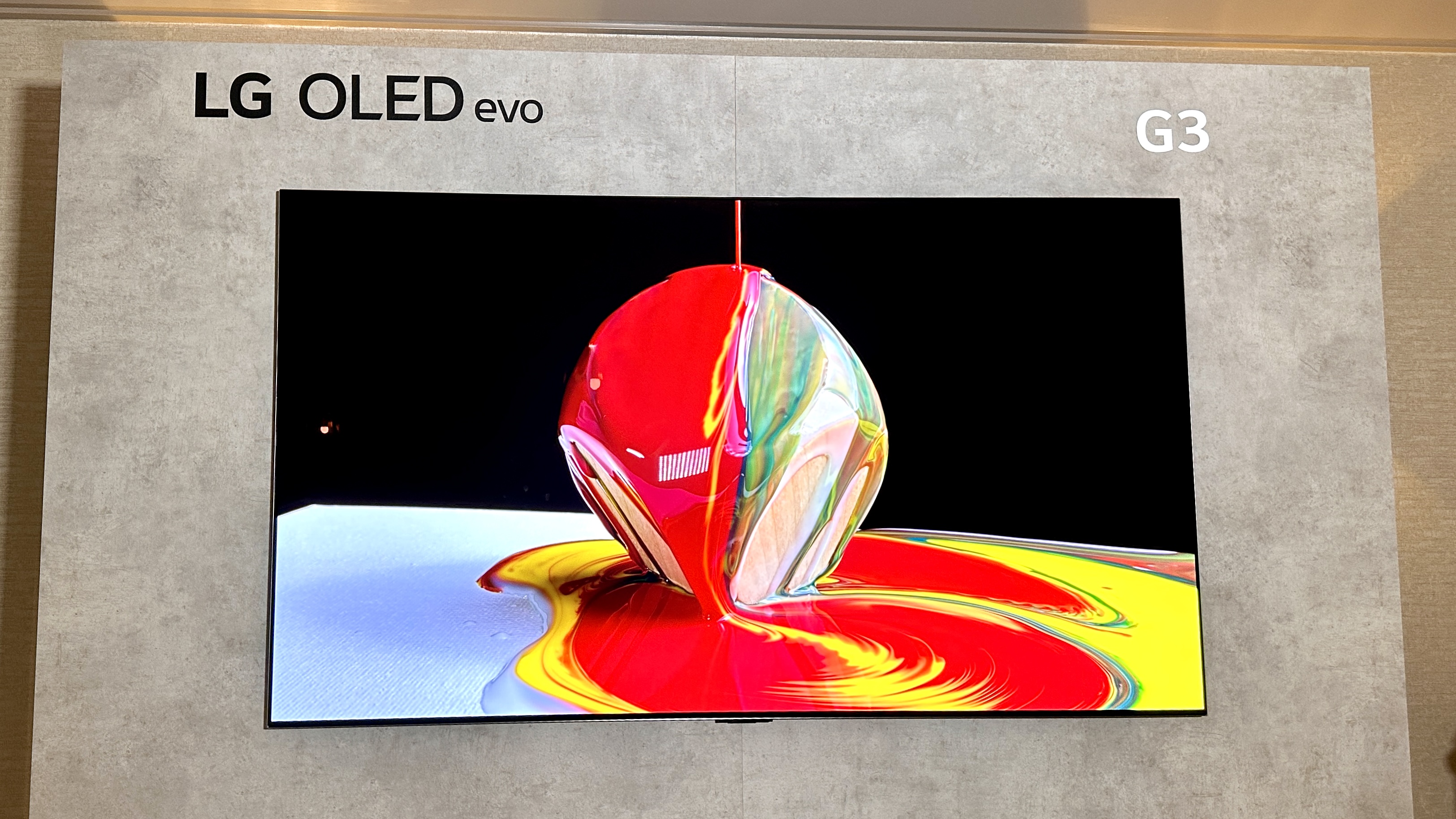 แสงสะท้อนเป็นลายรุ้งบนหน้าจอเคลือบเงาของ LG MRGB95B เมื่อเปิดไฟในห้อง