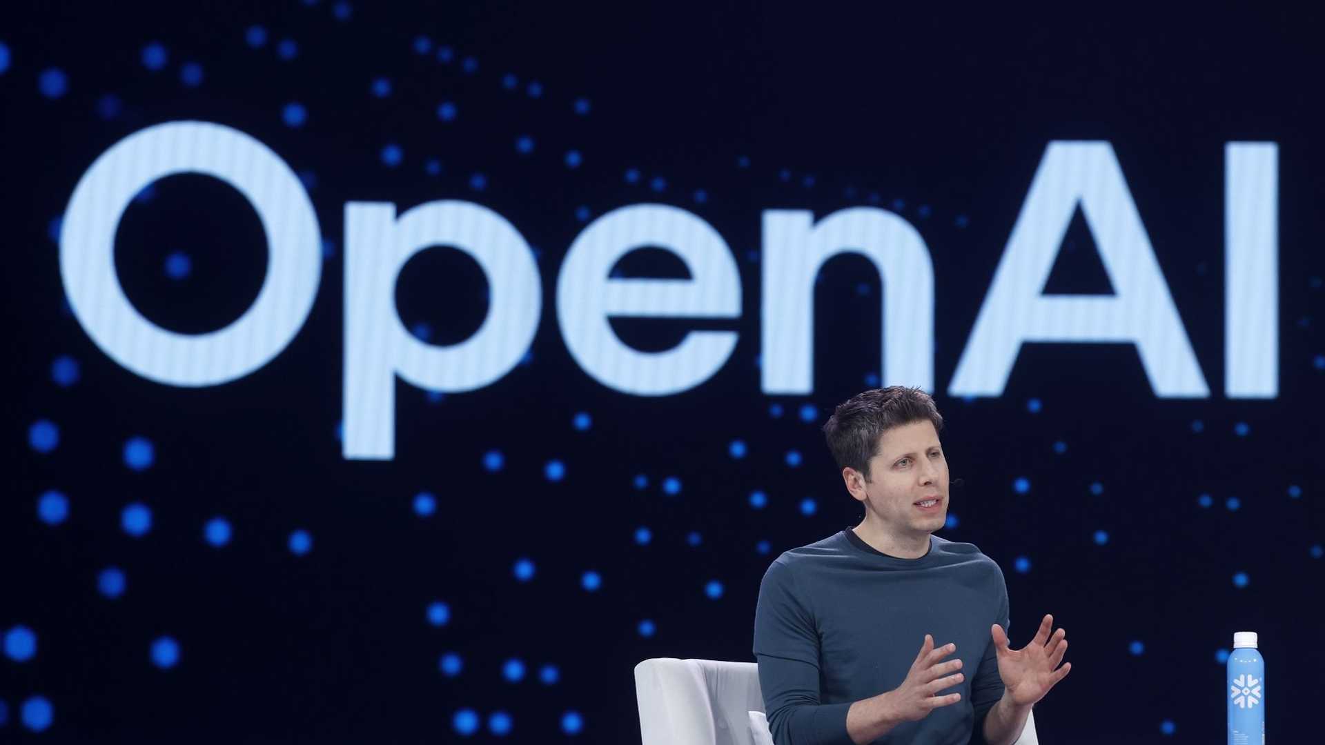 Sam Altman นั่งให้สัมภาษณ์บนเวทีที่มีโลโก้ OpenAI ขึ้นจอด้านหลัง